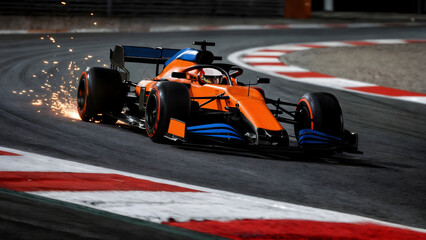 Orange Formula One car racing on racetrack, taking sharp curb with sparks flying from behind