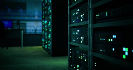 Rows of servers are visible in a dimly lit data center, with green lights blinking rhythmically. The atmosphere is tech focused, highlighting the high tech environment. © icetray
