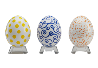 Three high-end porcelain Easter eggs, yellow polka dots, blue swirls, orange confetti, on acrylic stands, transparent background, studio lighting. Concept of luxurious product display