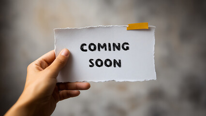 A Handheld Announcement: 'Coming Soon' on Torn Paper with a Yellow Sticky Tab
