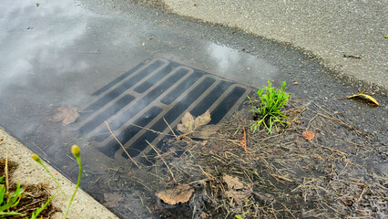Sewer grate flooded with rain water on the city road