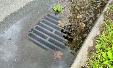 Sewer grate flooded with rain water on the city road