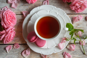 A cup of aromatic tea, a book and a rose on the table.