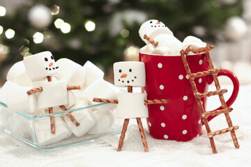 Christmas holiday scene featuring marshmallow snowmen  made from white marshmallows and pretzel sticks.  Selective focus. 