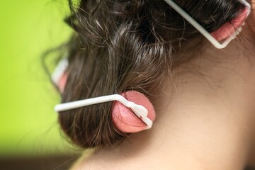 young girl with pink foam hair rollers and elastic bands for creating curls