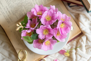 A cup of aromatic tea, a book and a rose on the table.