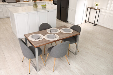 Kitchen interior with dining table, place setting and grey chairs