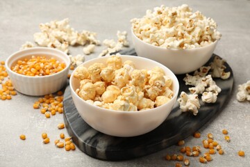 Tasty popcorn and corn kernels on light grey table, closeup