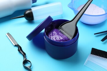 Care cosmetic product for blonde hair in jar and hairdresser's tools on light blue background, closeup