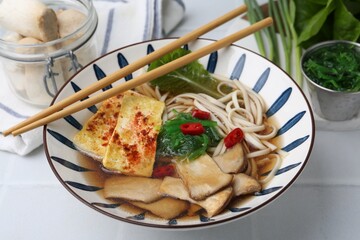 Tasty ramen with king oyster (eryngii) mushrooms in bowl on light table, closeup