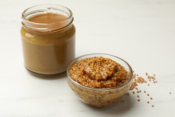 Whole grain mustard and sauce on white marble table, closeup