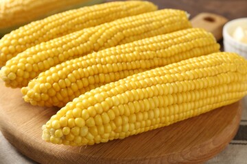Tasty boiled corncobs on wooden table, closeup