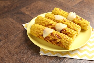 Tasty grilled corncobs with sauce on wooden table, closeup