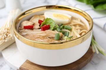Tasty ramen with enoki and king oyster (eryngii) mushrooms on white marble table, closeup