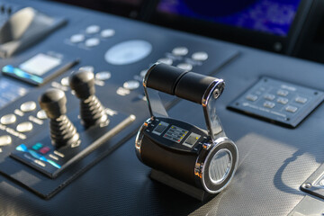 A close-up view of a yacht or ship bridge with the throttle controls. The navigation radar screen...