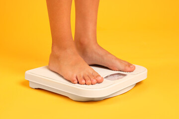 Little boy standing on scales against orange background, closeup