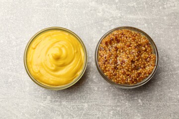Different types of mustard on light grey table, flat lay