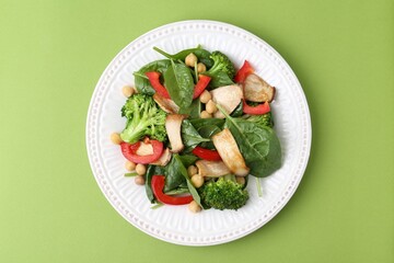 Tasty salad with eryngium mushrooms, chickpeas, vegetables and spinach on green background, top view