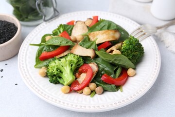 Tasty salad with eryngium mushrooms, chickpeas, vegetables and spinach on light table, closeup