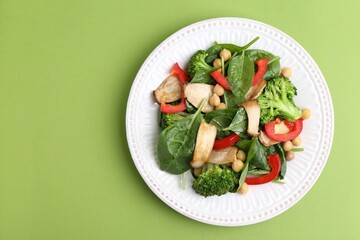 Tasty salad with eryngium mushrooms, chickpeas, vegetables and spinach on green background, top view. Space for text