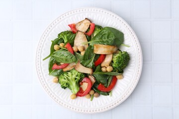 Tasty salad with eryngium mushrooms, chickpeas, vegetables and spinach on white tiled table, top view