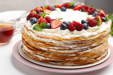 Delicious crepe cake with fresh berries on white table, closeup