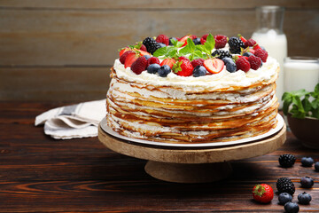 Delicious crepe cake with fresh berries on wooden table