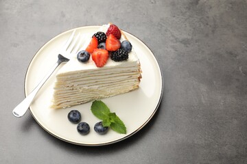 Piece of tasty crepe cake with berries on grey table. Space for text