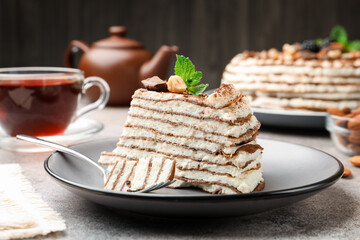 Piece of tasty crepe cake with cocoa powder, chocolate and nuts served on light table, closeup