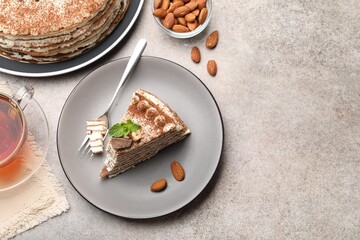 Piece of tasty crepe cake with cocoa powder, chocolate and nuts served on light table, flat lay. Space for text