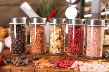 Different spices and glass jars and on wooden table, closeup