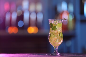 Glass of alcoholic cocktail on table against blurred background, space for text