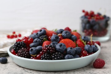 Different ripe berries on light grey textured table, closeup