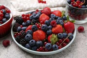 Different ripe berries on light grey textured table, closeup