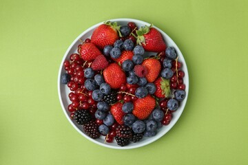 Different ripe berries on green background, top view