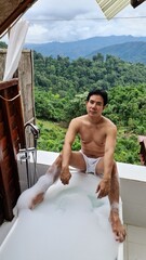 Man relaxing in a bubble bath with a mountain view on a transparent background