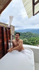 Man relaxing in an outdoor bubble bath with a mountain view on a transparent background
