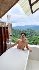 Man enjoying a luxurious bubble bath outdoors with a scenic view on a transparent background