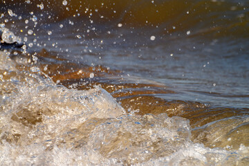 Waves Crashing on Beach Rocks. White sea foam waves striking rocky shoreline.