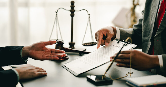 concept of justice and law A male judge in the courtroom on a wooden table and a male counselor or lawyer working in the office. Law, advice and justice concepts. - Powered by Adobe