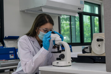 Young scientist examines samples using a microscope in a modern laboratory setting during daylight hours