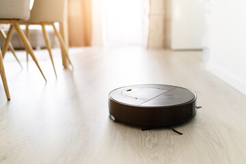 Robotic vacuum cleaner working on wooden floor in bright modern home. Concept of smart home cleaning, automation, and technology convenience for lifestyle