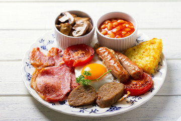 Classic traditional Irish or English breakfast with sausages, bacon rashers, white pudding, beans and grilled tomatoes