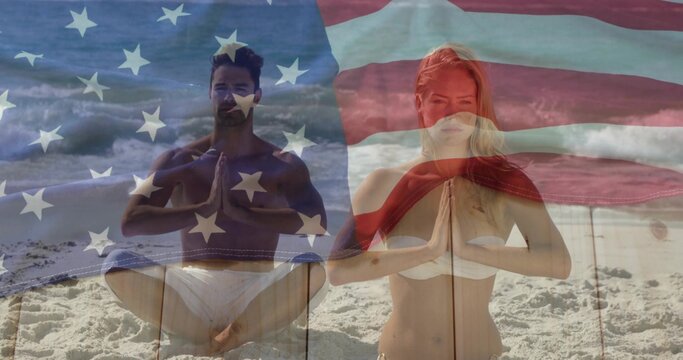 Sitting couple wearing swimwear in prayer pose at beach, with ocean waves and USA flag overlay - Powered by Adobe