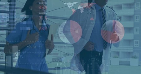 Walking scrub-clad nurse and suited doctor analyzing digital charts in corridor with stethoscopes