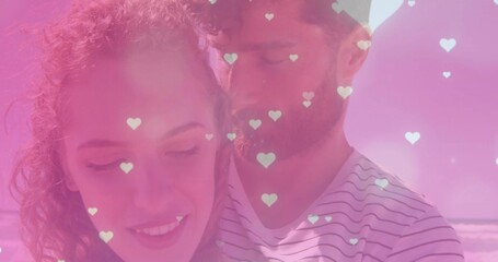 Embracing romantic couple hugging on sandy beach shoreline, with digital heart-shaped graphics