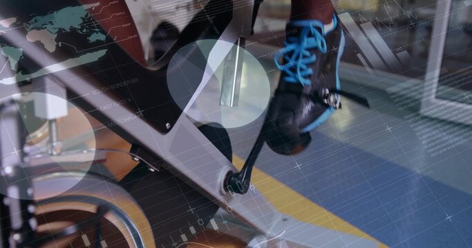 Pedaling foot in black cycling shoe with blue laces on stationary bike at gym, digital overlays