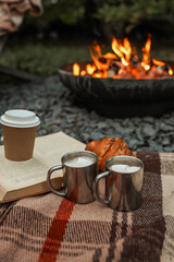Cozy outdoor scene with coffee, marshmallows, and a crackling fire