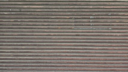 Old rolling steel doors of shops, closed and locked steel doors, warehouse doors, storage room doors, antique rolling steel doors, peeling paint, scratches, and stains.