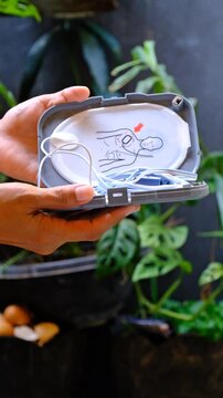 Automatic external defibrillator. Portable defibrillator on a wooden table. Defibrillator for medical care. Device for provision of emergency medical care. Automatic cardioverter with nursing manual
